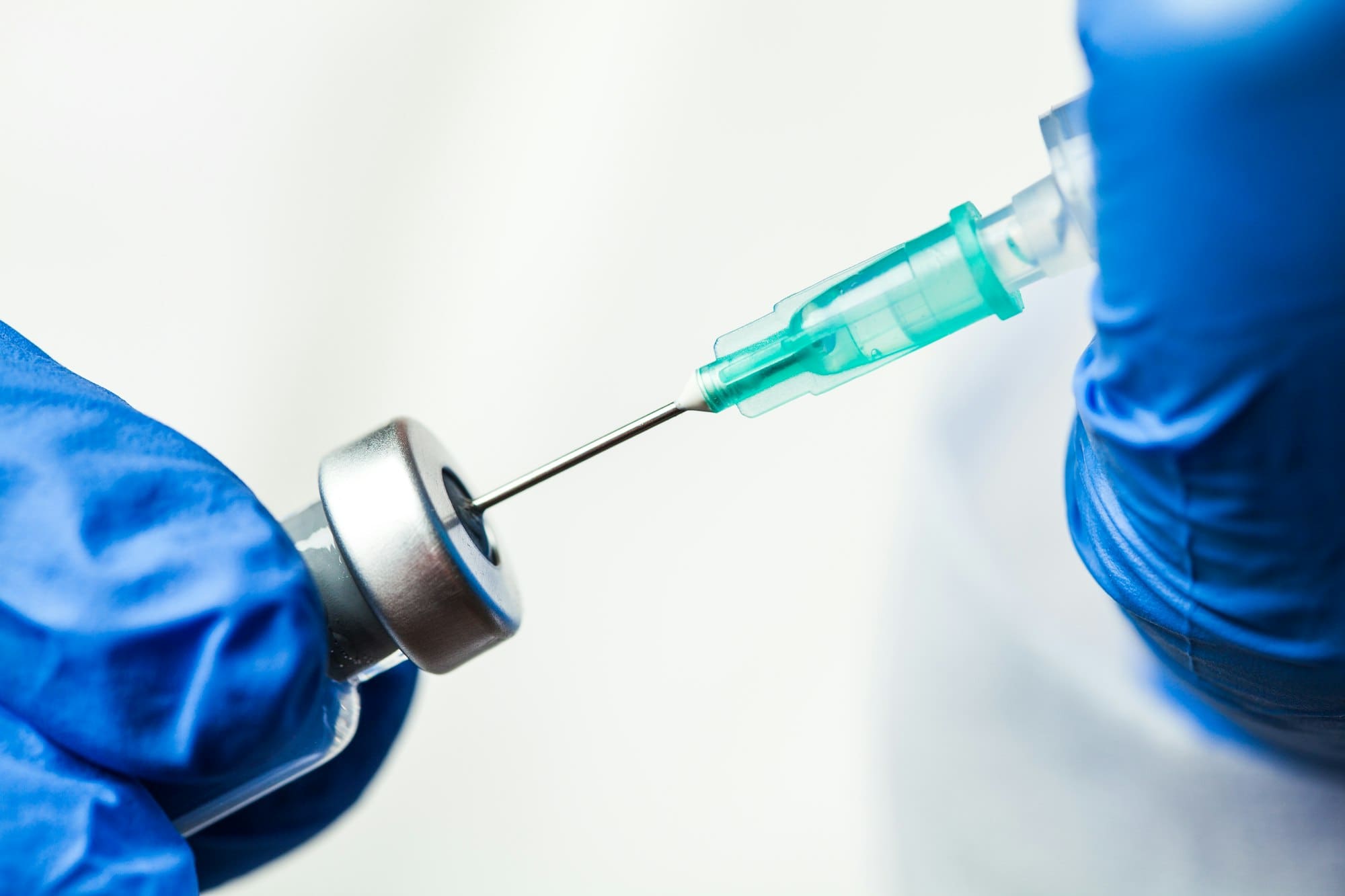 Detail closeup of syringe needle in ampoule vial,UK nurse taking injection shot